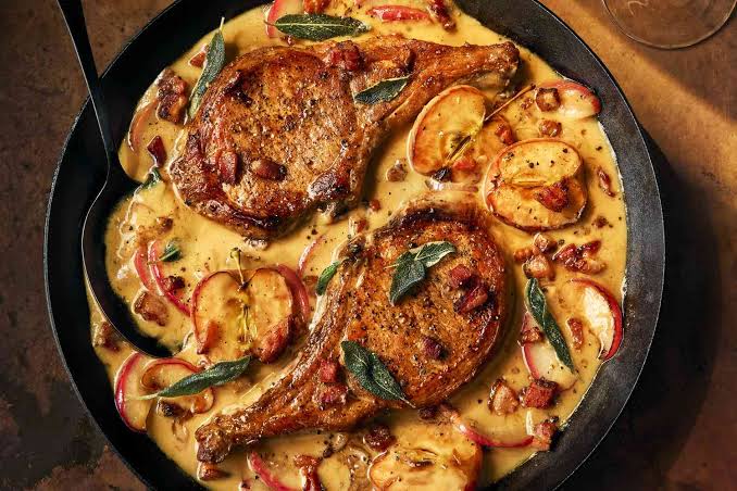 Seared pork chops with apples and sage in a skillet